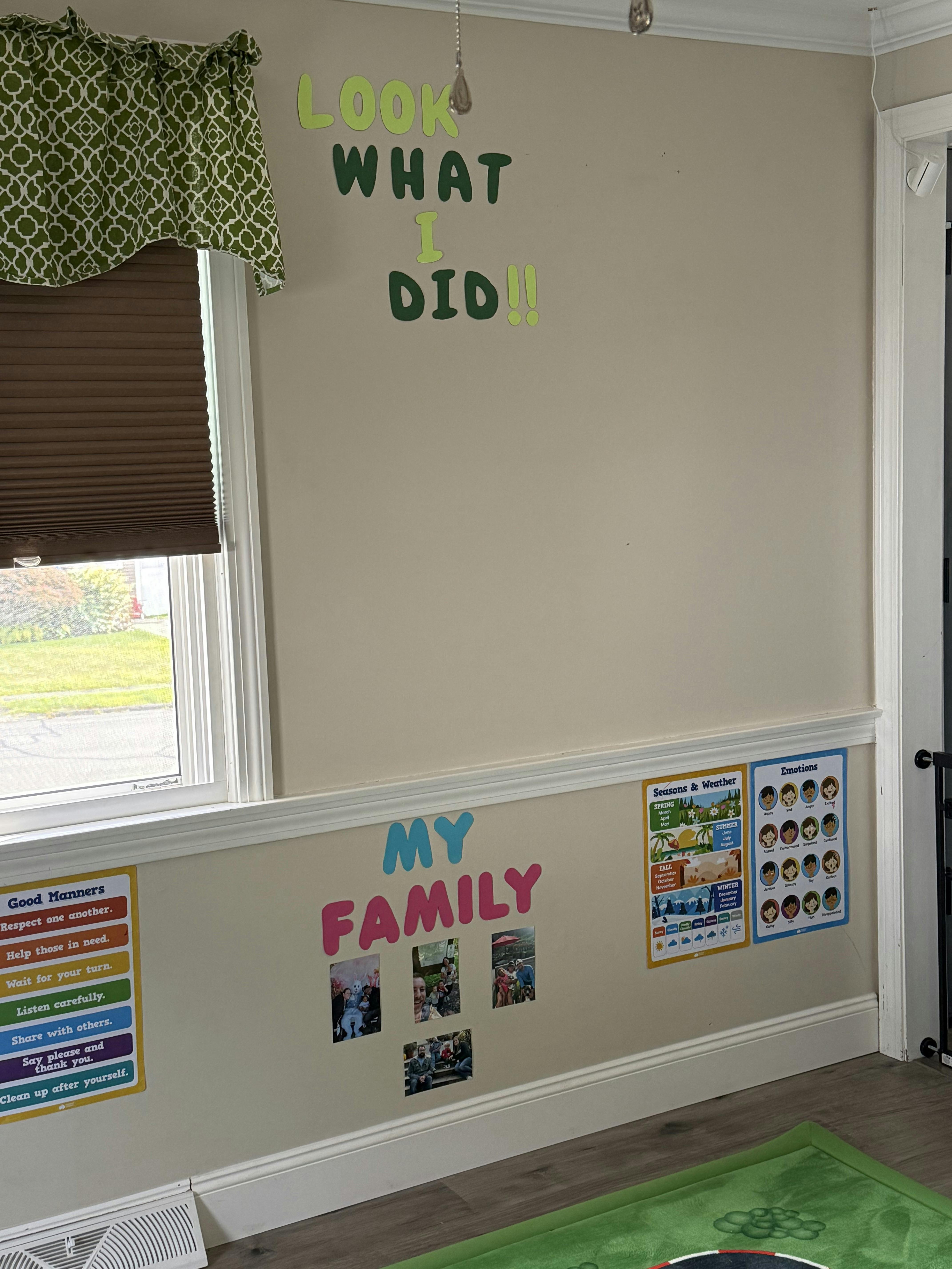 Wall with "Look What I Did" and "My Family" signs, photos, and charts