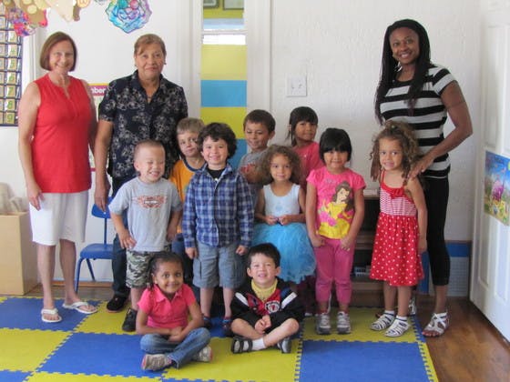 Three adults and multiple children posing for a group photo indoors