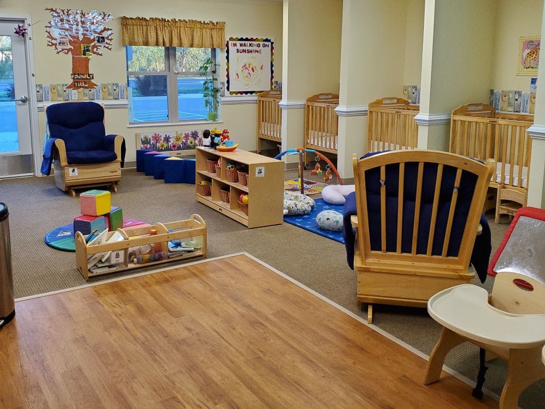 cribs in a daycare or nursery room with rocking chairs and toys