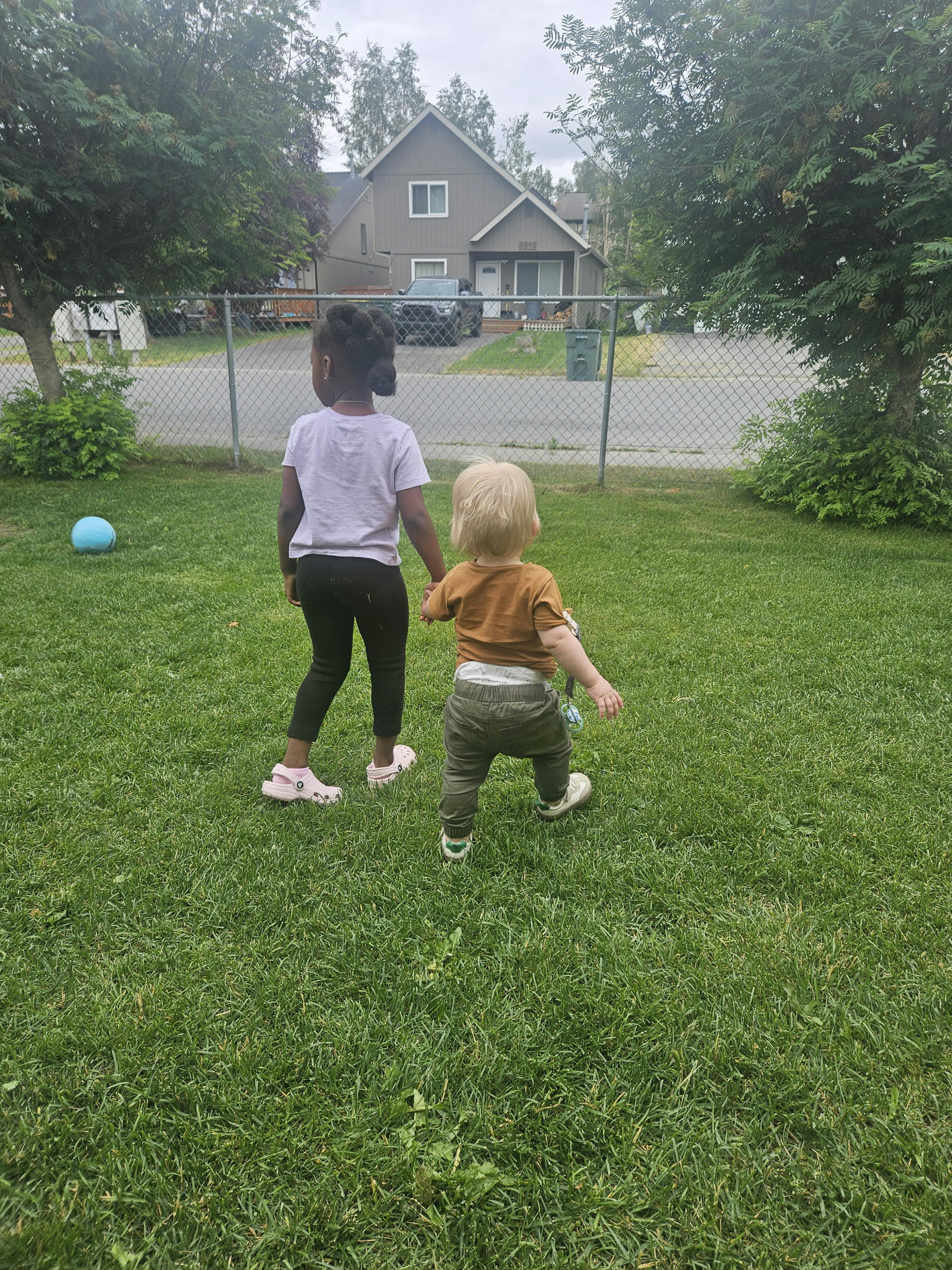 Child and toddler walking on grass