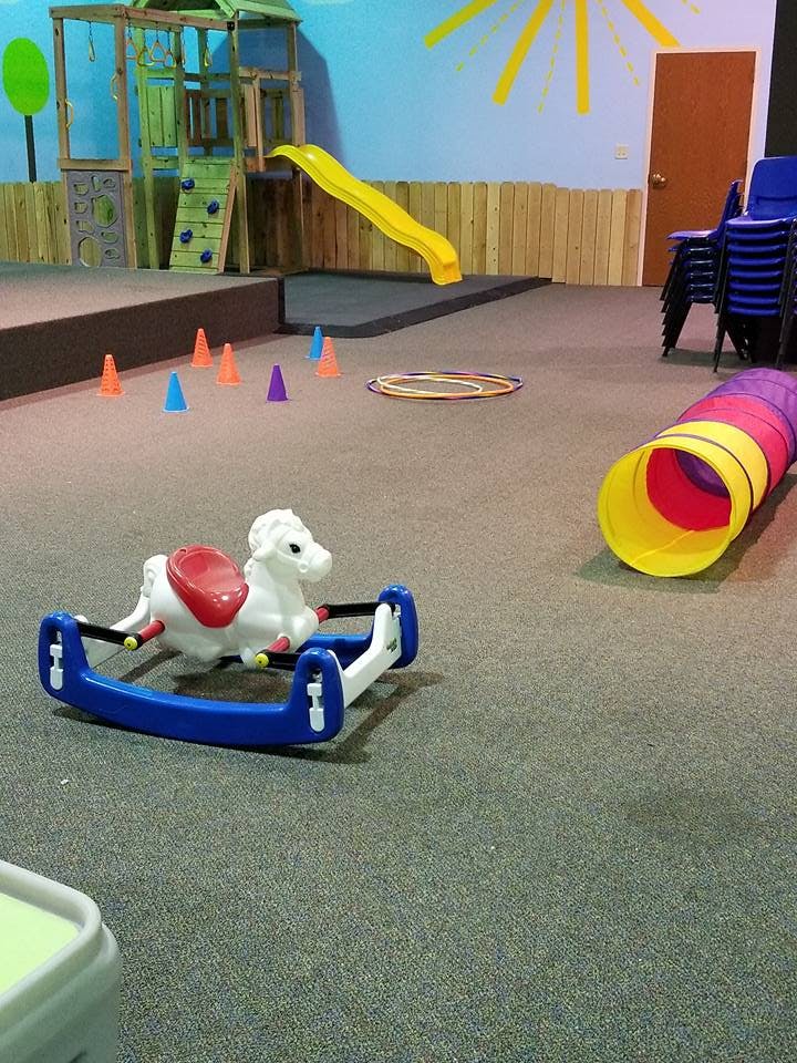 Indoor play area with a rocking horse, play structure, slide, and tunnel