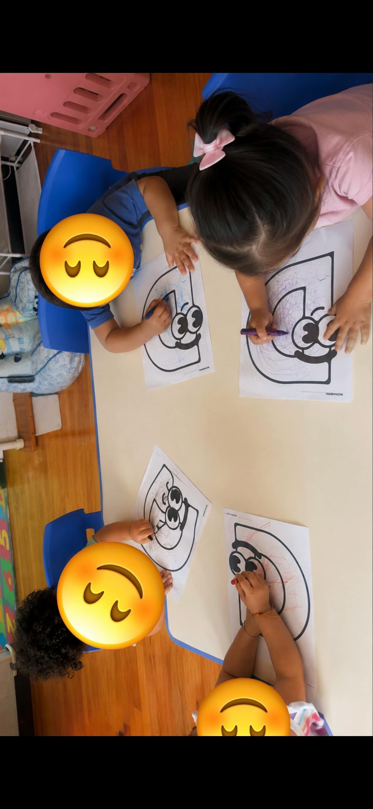 Four children coloring letter D worksheets at a table