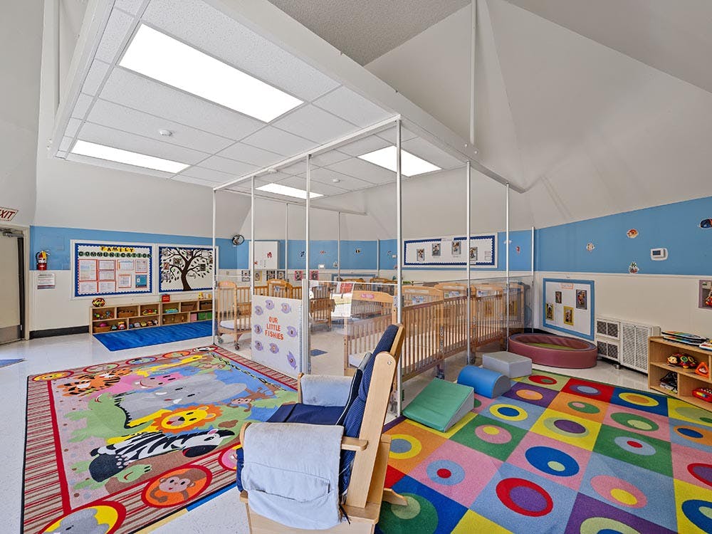 Colorful daycare room with cribs and play areas