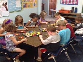 Children playing a board game at a table in a classroom
