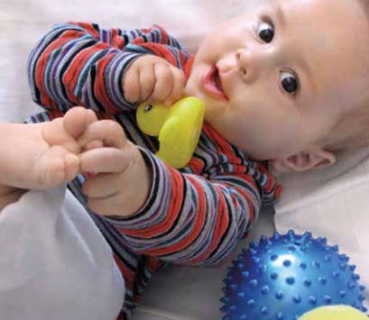 Child in striped shirt holding a yellow toy