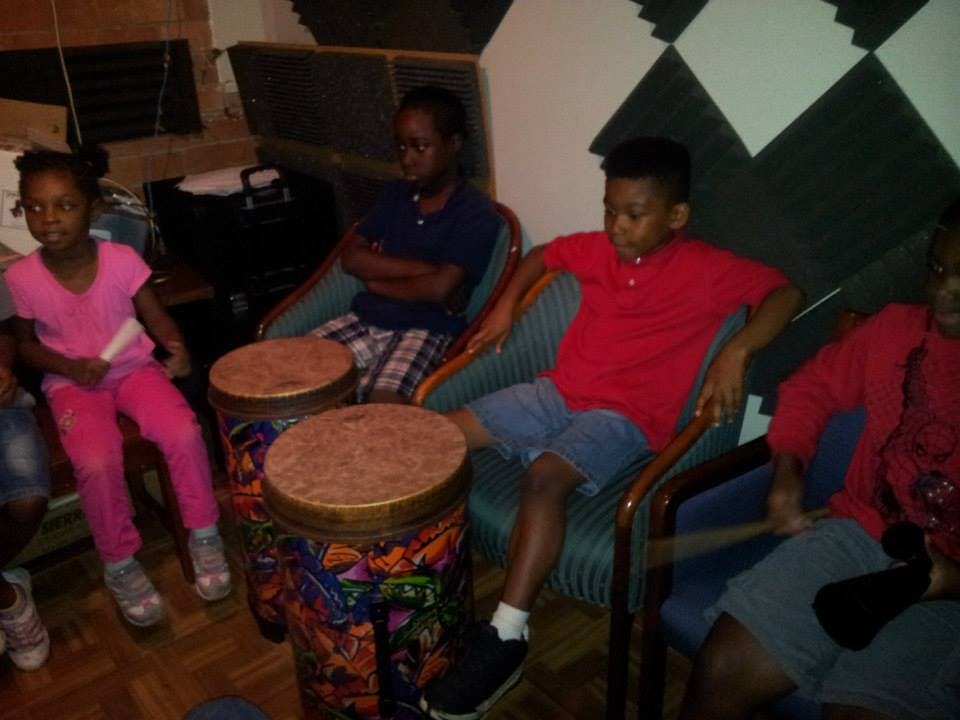 Three children and a teen sitting with two drums