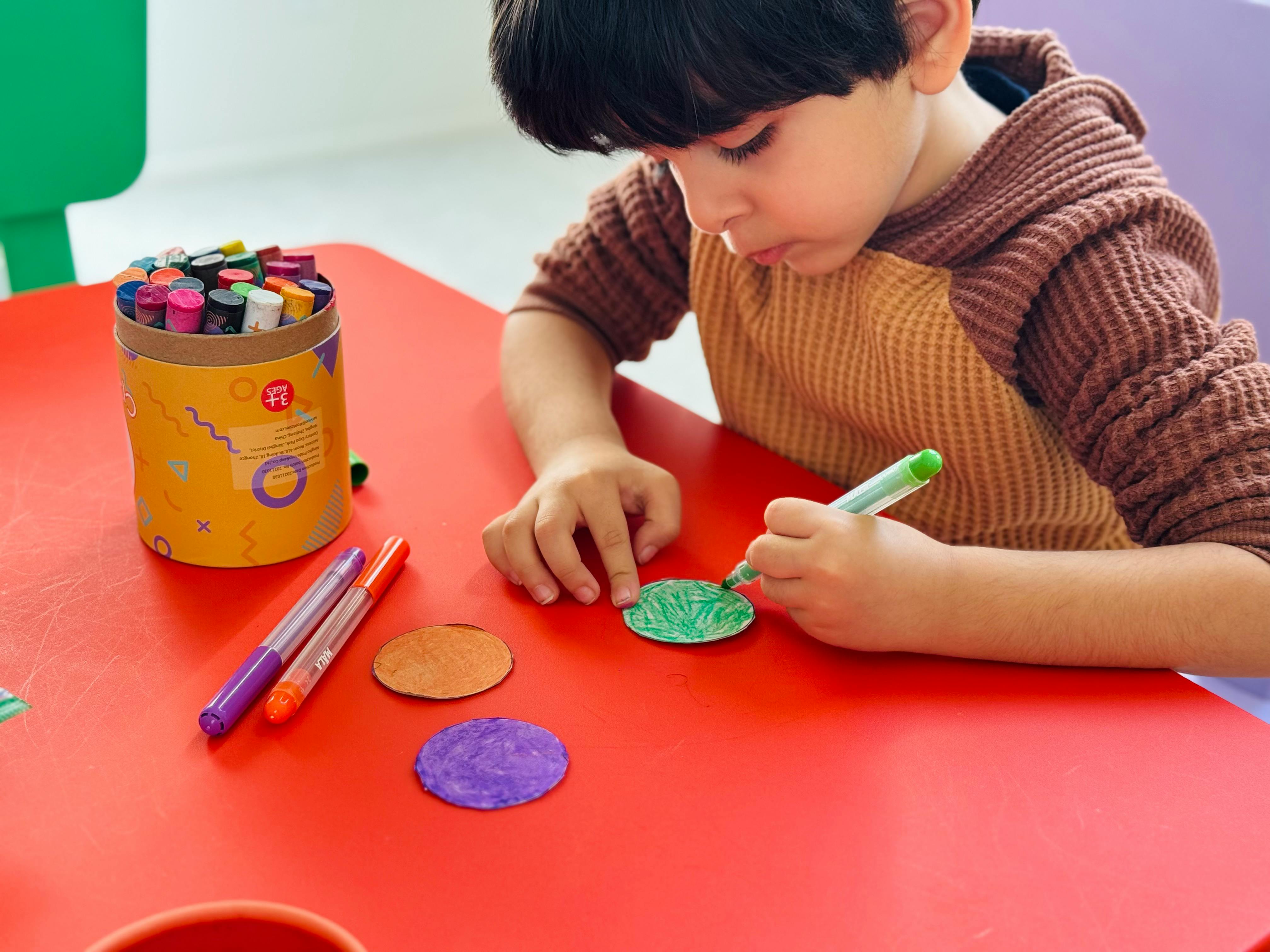 Child coloring a paper circle with a marker