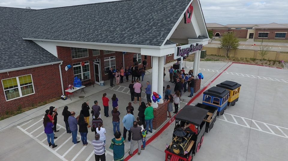 People gathered outside a building with a small train