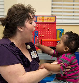 Adult and child interacting, child reaching for adult's mouth
