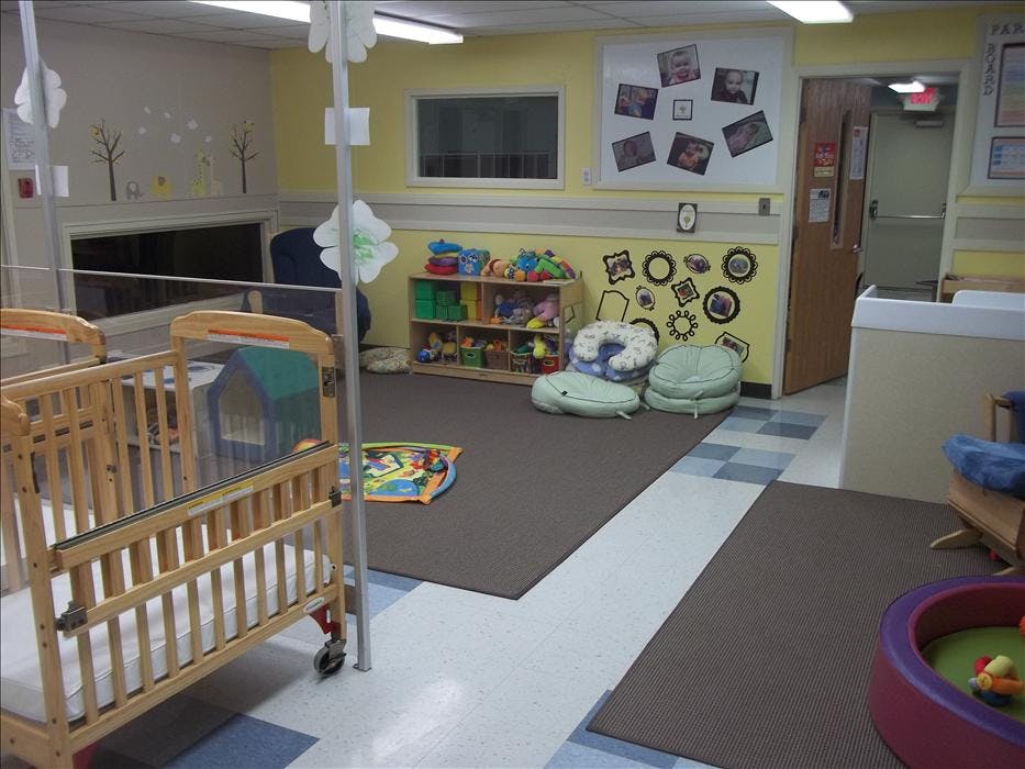 Cribs, infant play mats, and small storage shelves in a daycare room
