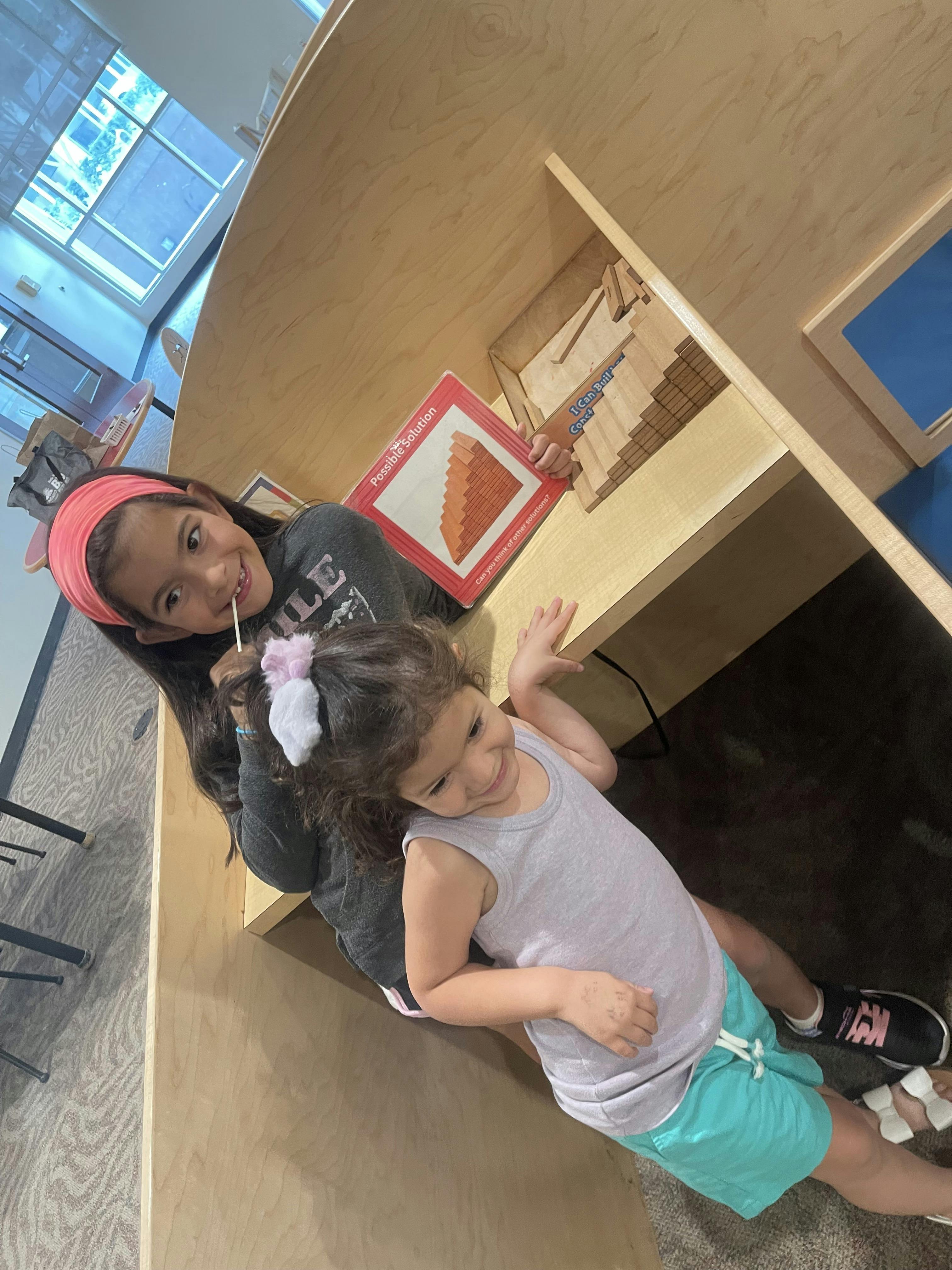 Two children playing with building blocks in a wooden cubby