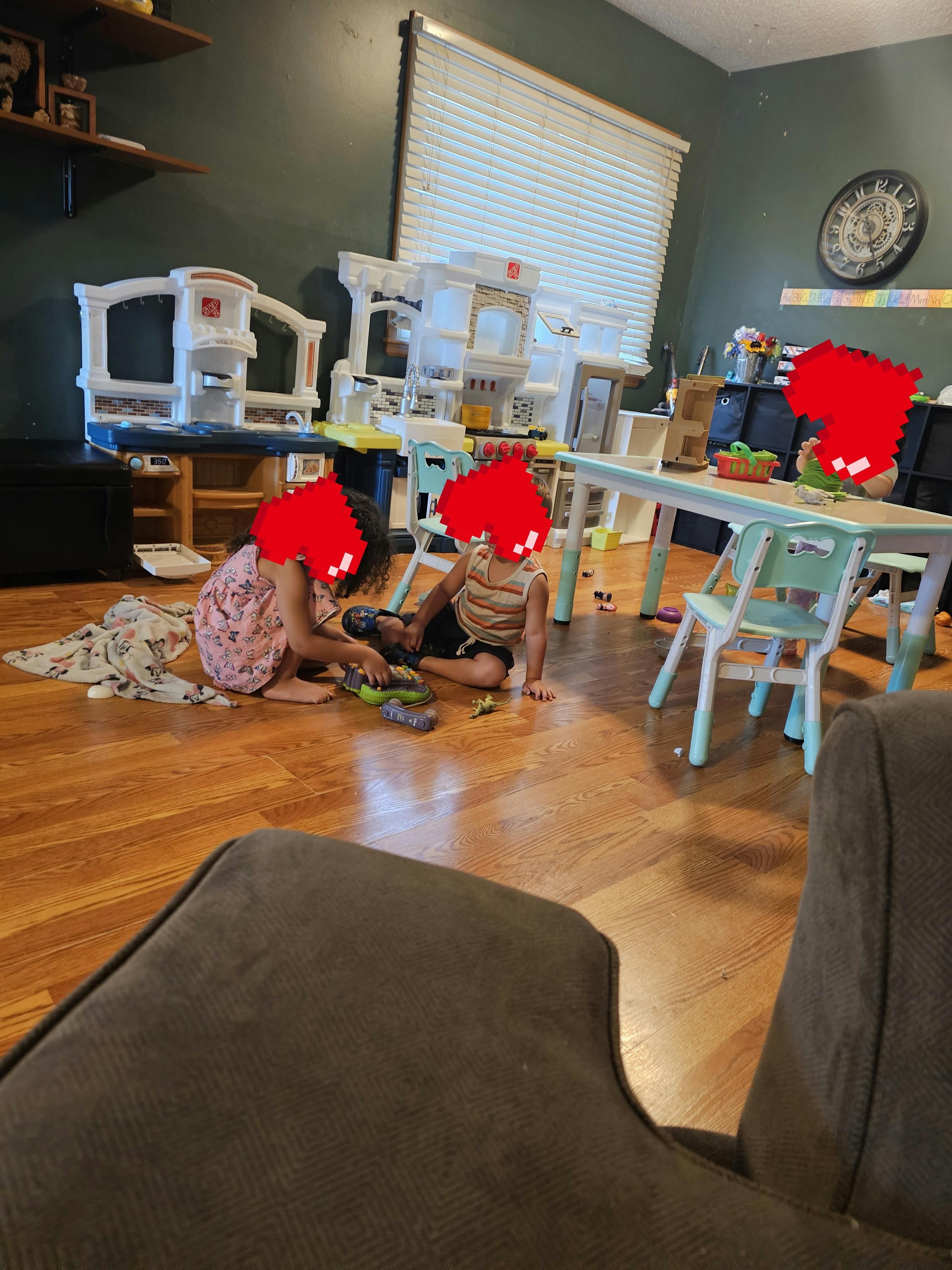 Two children playing with toys on a wooden floor
