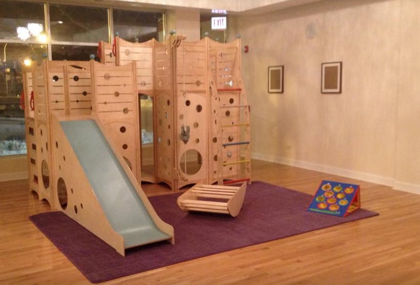 Indoor wooden play structure with a slide and climbing features