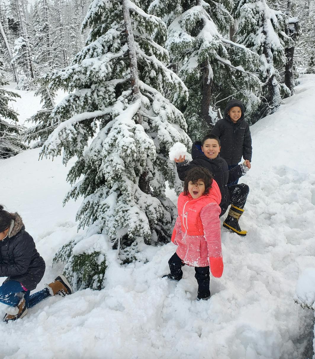 Children playing in snow with snow-covered trees