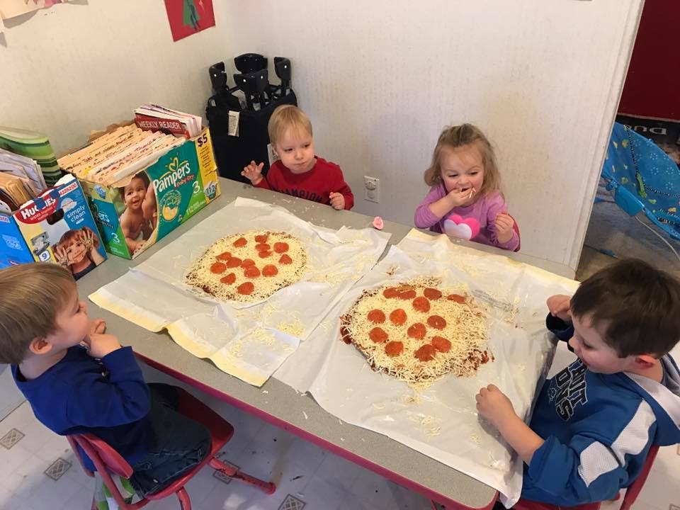 Four children at a table with two pizzas