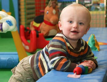 Child in striped shirt crawling on blue mat