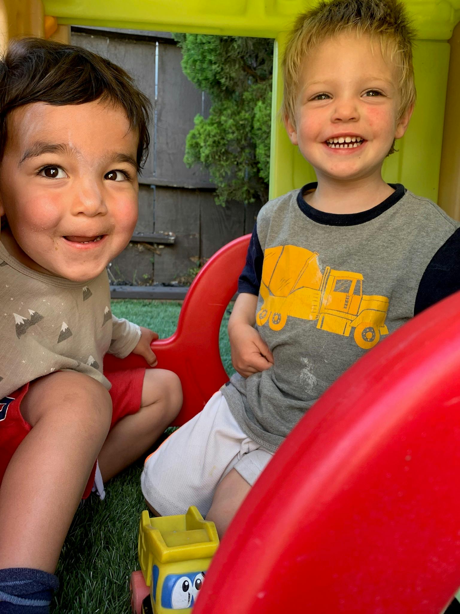 Two children sitting on a red play structure