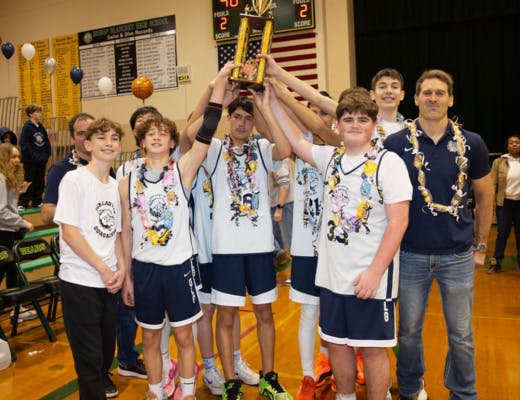 Group of young people in basketball uniforms holding up a trophy