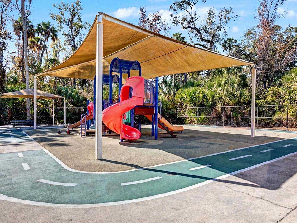 Playground with slides and climbing structure under a shade canopy