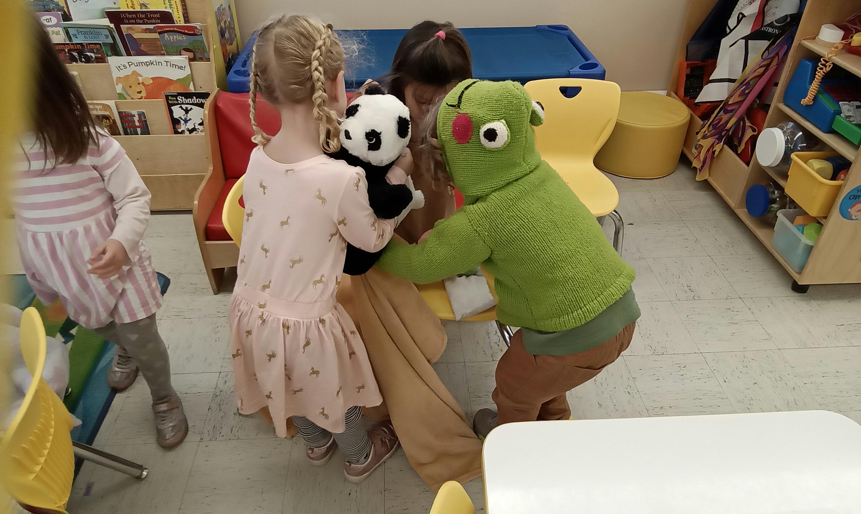 Children playing with a panda puppet and a green monster puppet