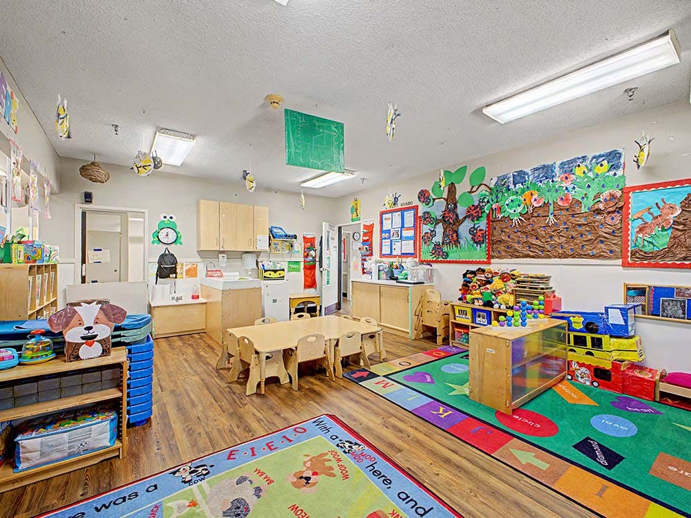 Colorful playroom with small tables and chairs, shelves, and art on walls