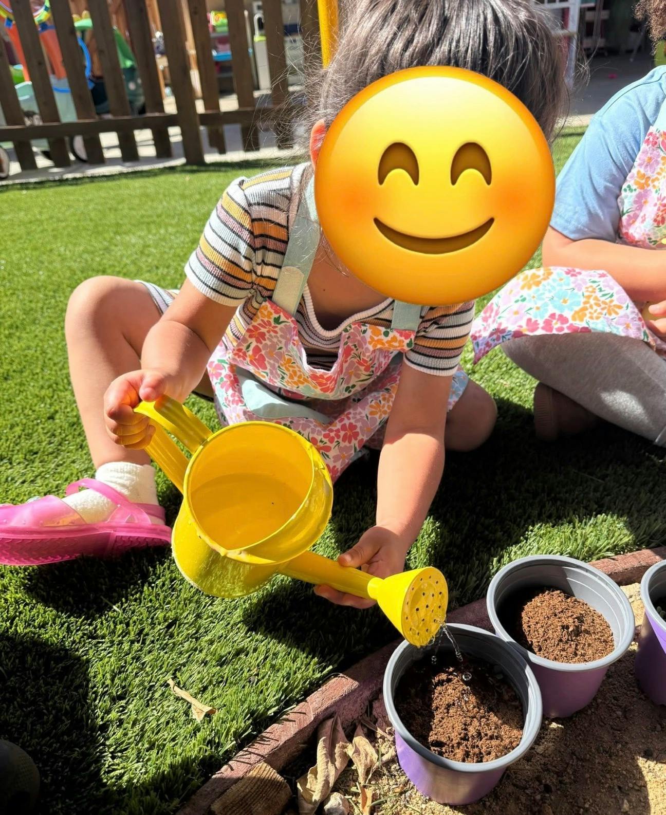 Child watering potted plants with a yellow watering can