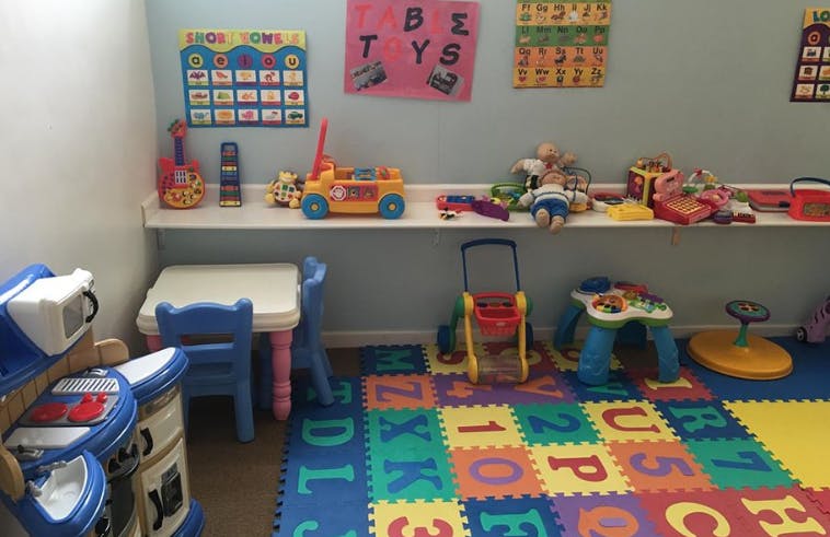Children's play area with toys, small table and chairs, and alphabet floor mats