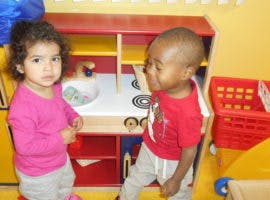 Two children playing with a toy kitchen