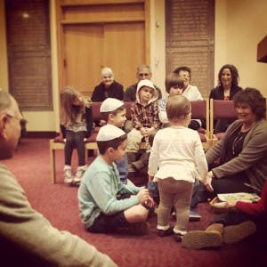 People and children sitting on the floor and chairs