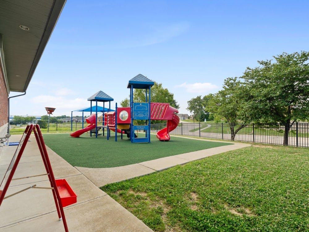 Empty red and blue playground with slides on green turf