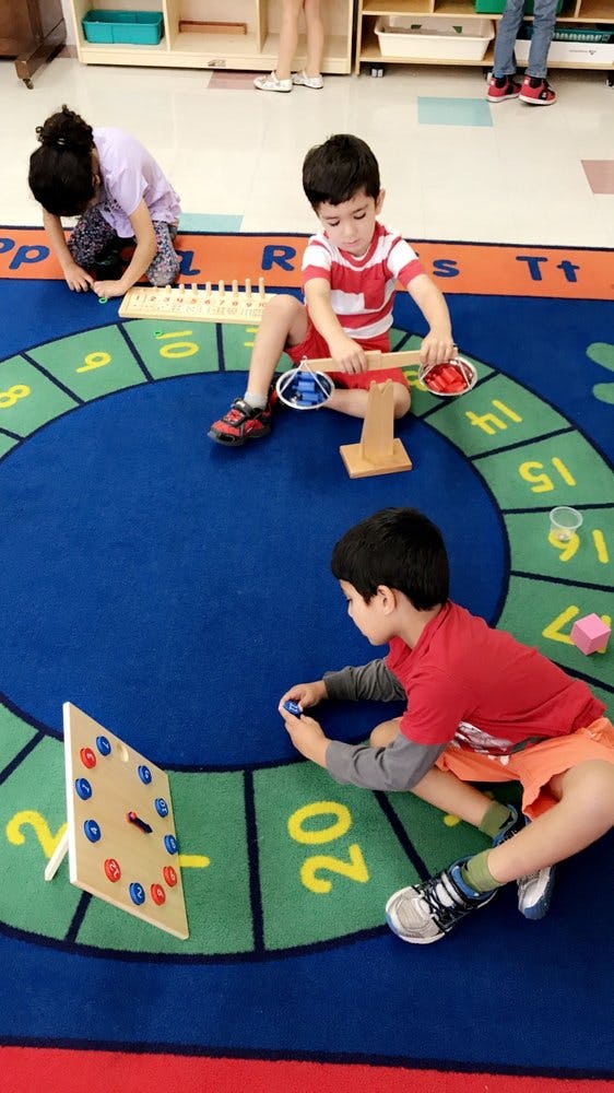 Children playing with educational toys on a numbered rug