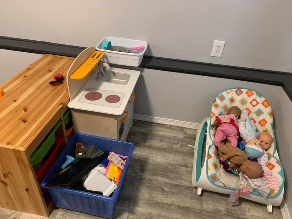 Play kitchen with a wooden storage unit and a baby bouncer with dolls