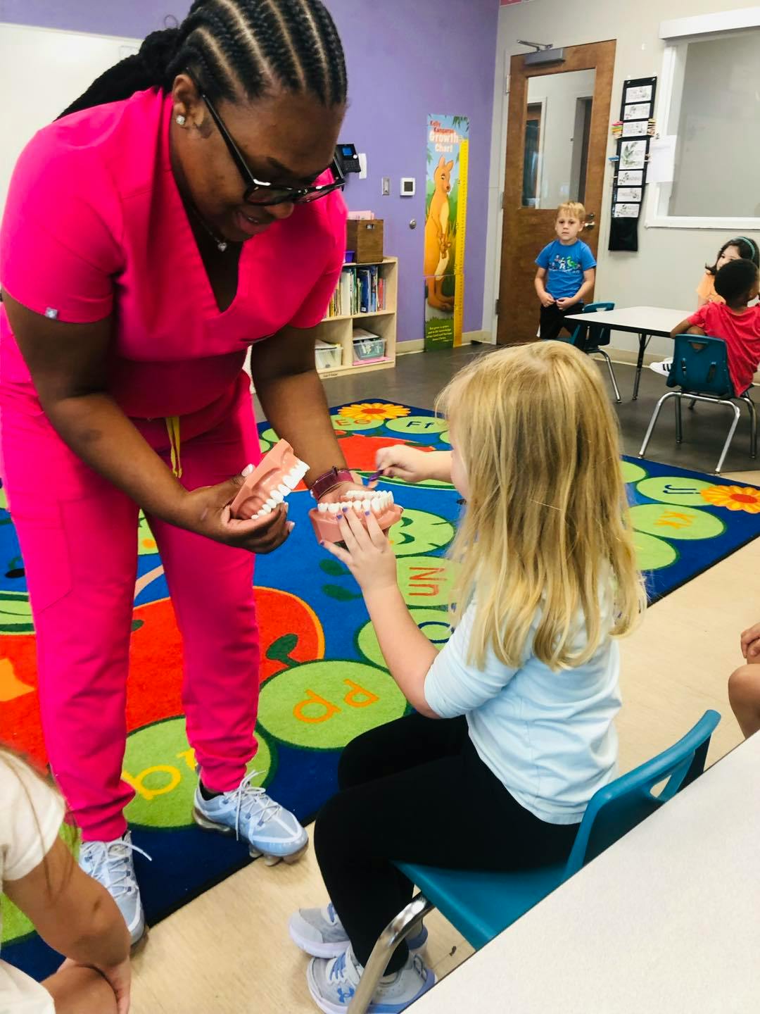 Person in scrubs showing a child a dental model