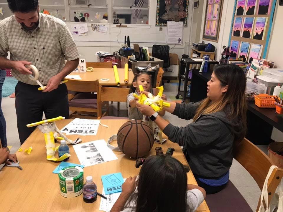 Adults and children at a table with craft supplies and a basketball