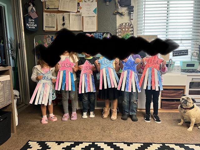 Children holding up USA-themed crafts, red, white, and blue paper crafts