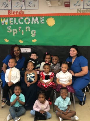 Two people with a group of children in a classroom