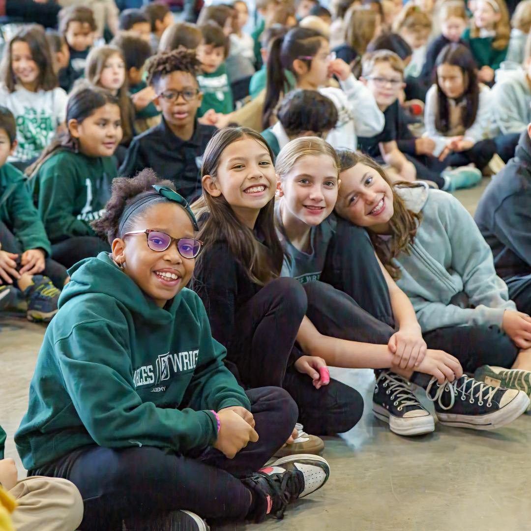 Group of children sitting on the floor, some looking at the camera