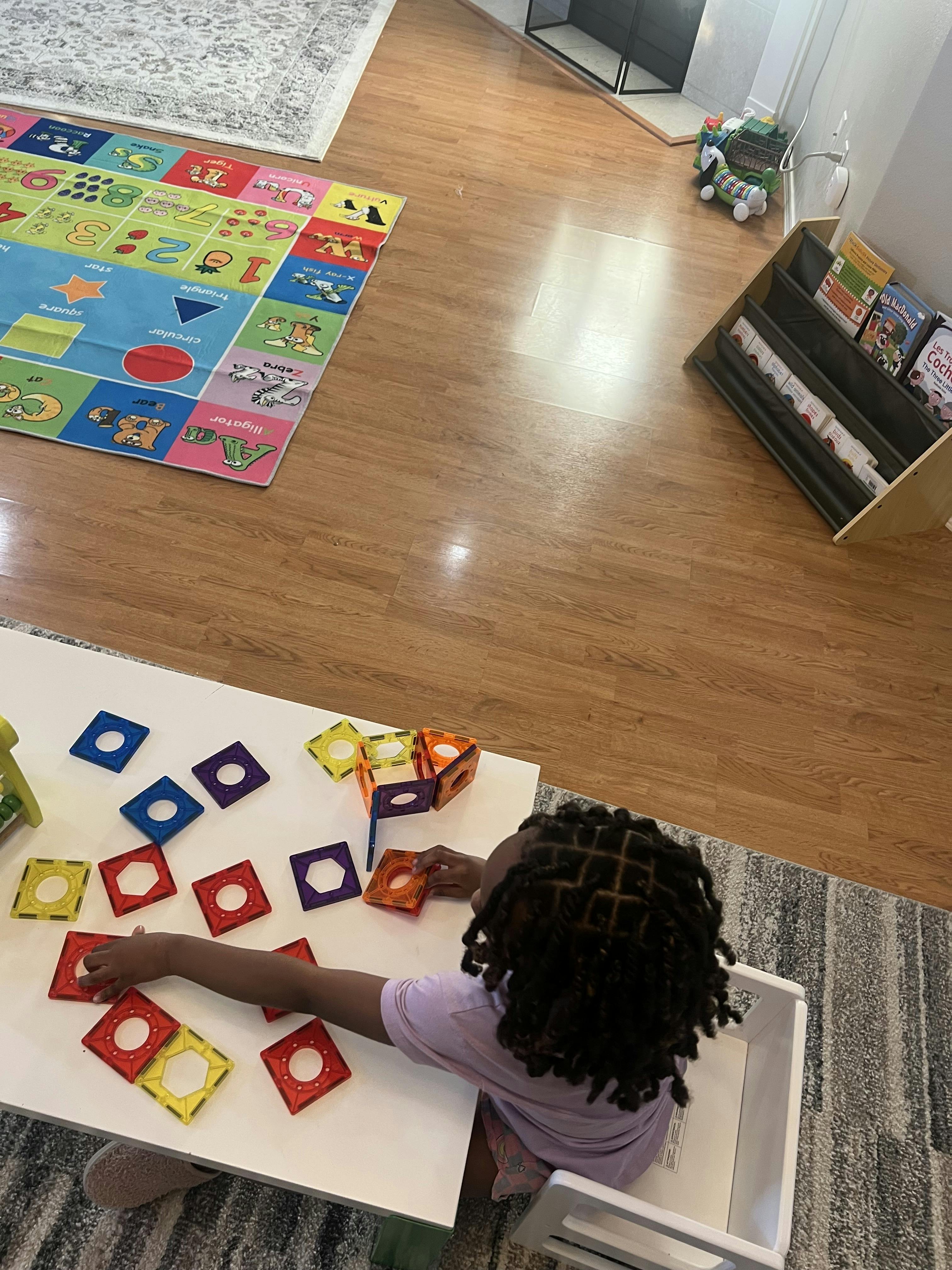 Child playing with colorful magnetic tiles at a table