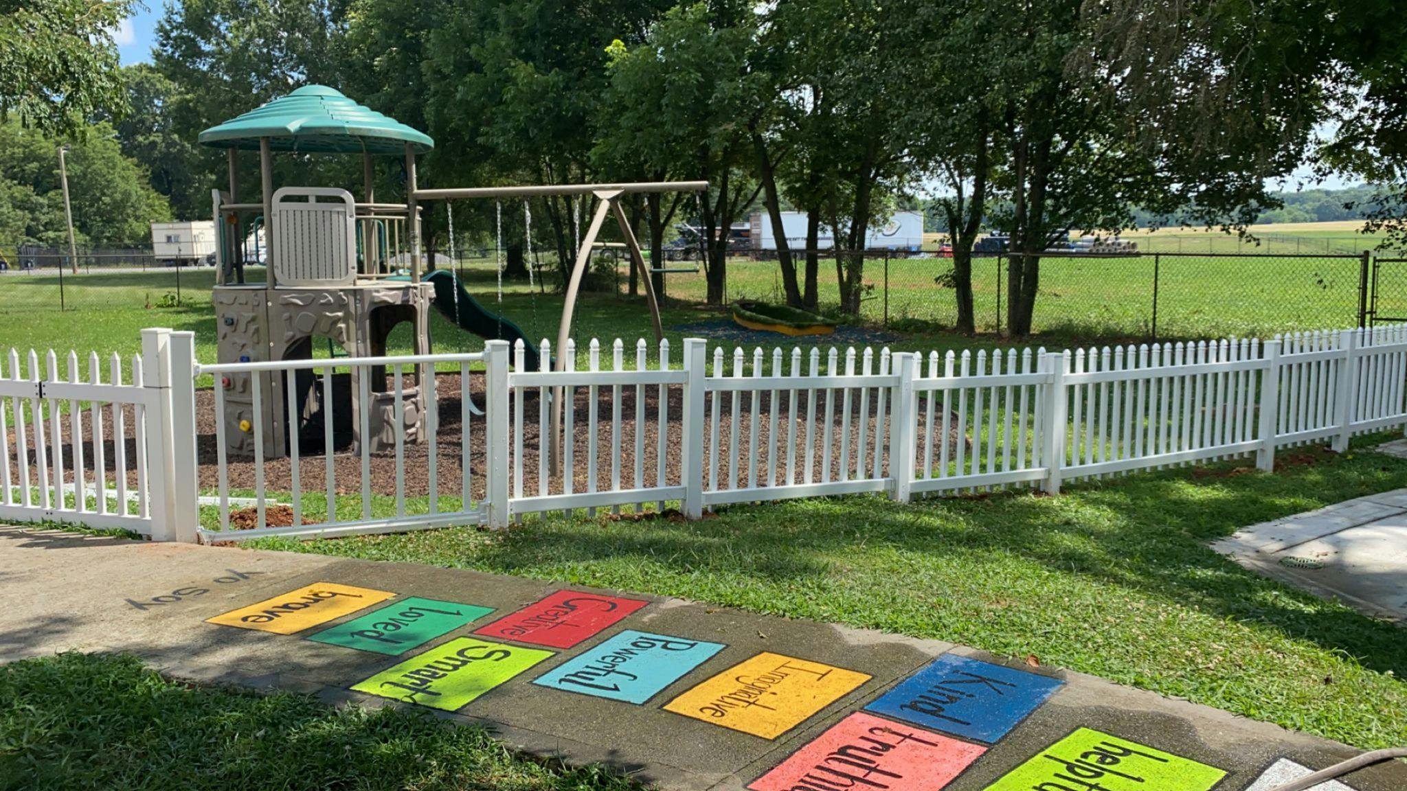 Playground with a white picket fence and colorful squares on the ground