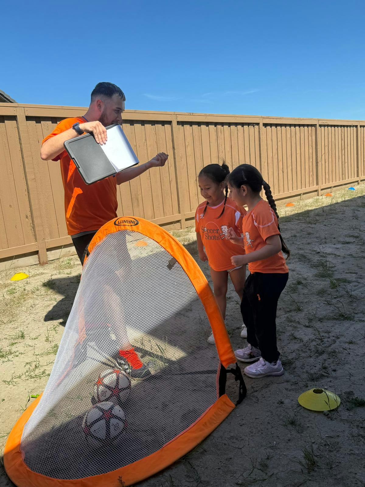 Person holding a tablet with two children next to a soccer goal