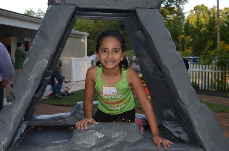 Child in a green tank top looking out from an inflatable structure
