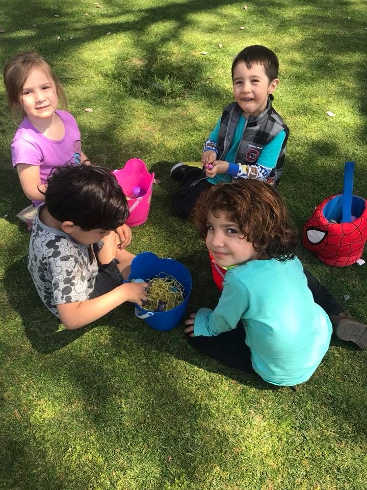 Four children sitting on grass with baskets