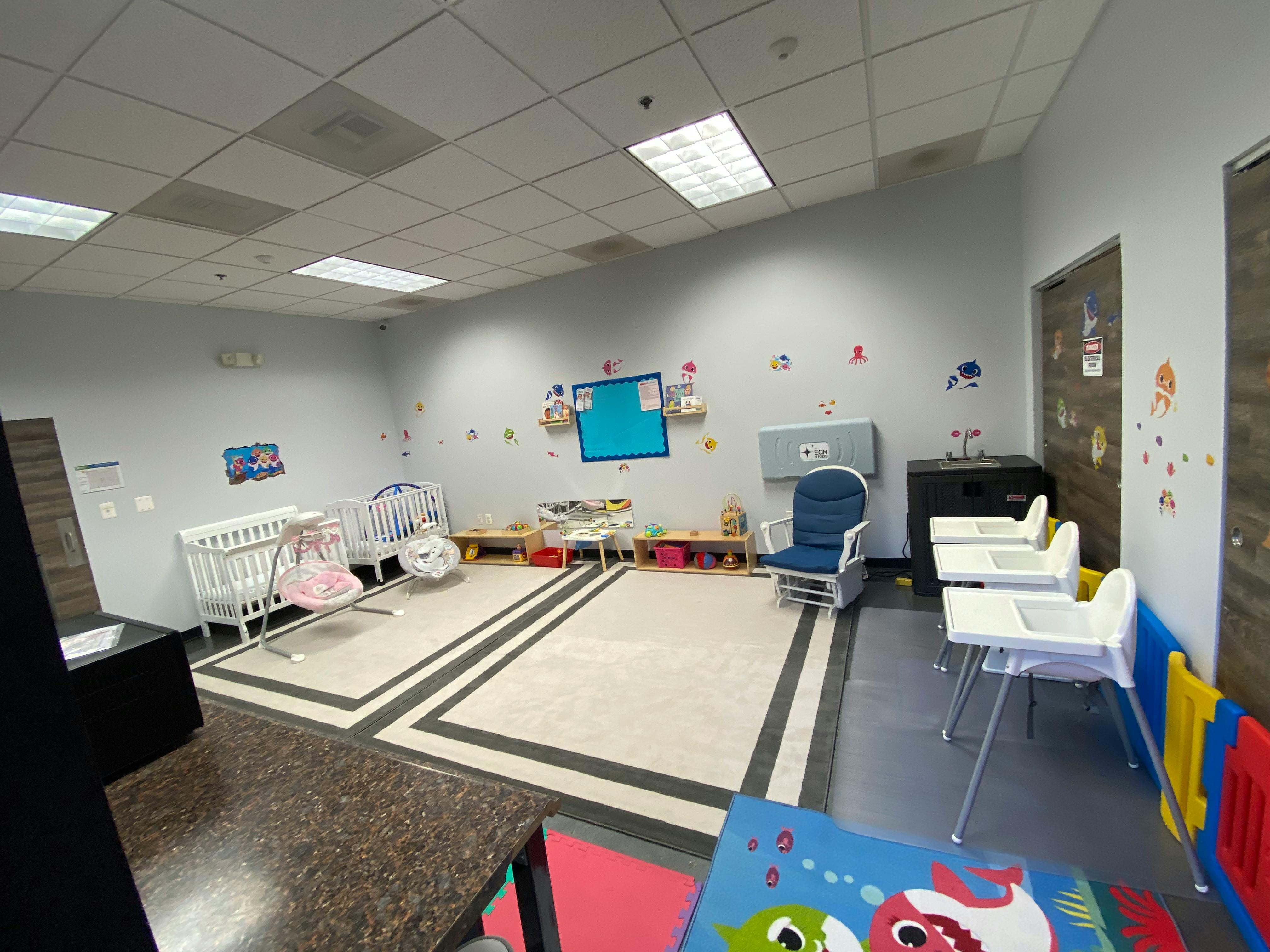 Infant room with cribs, high chairs, and play mats