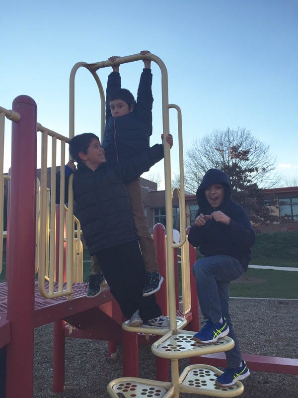 Three children playing on playground equipment