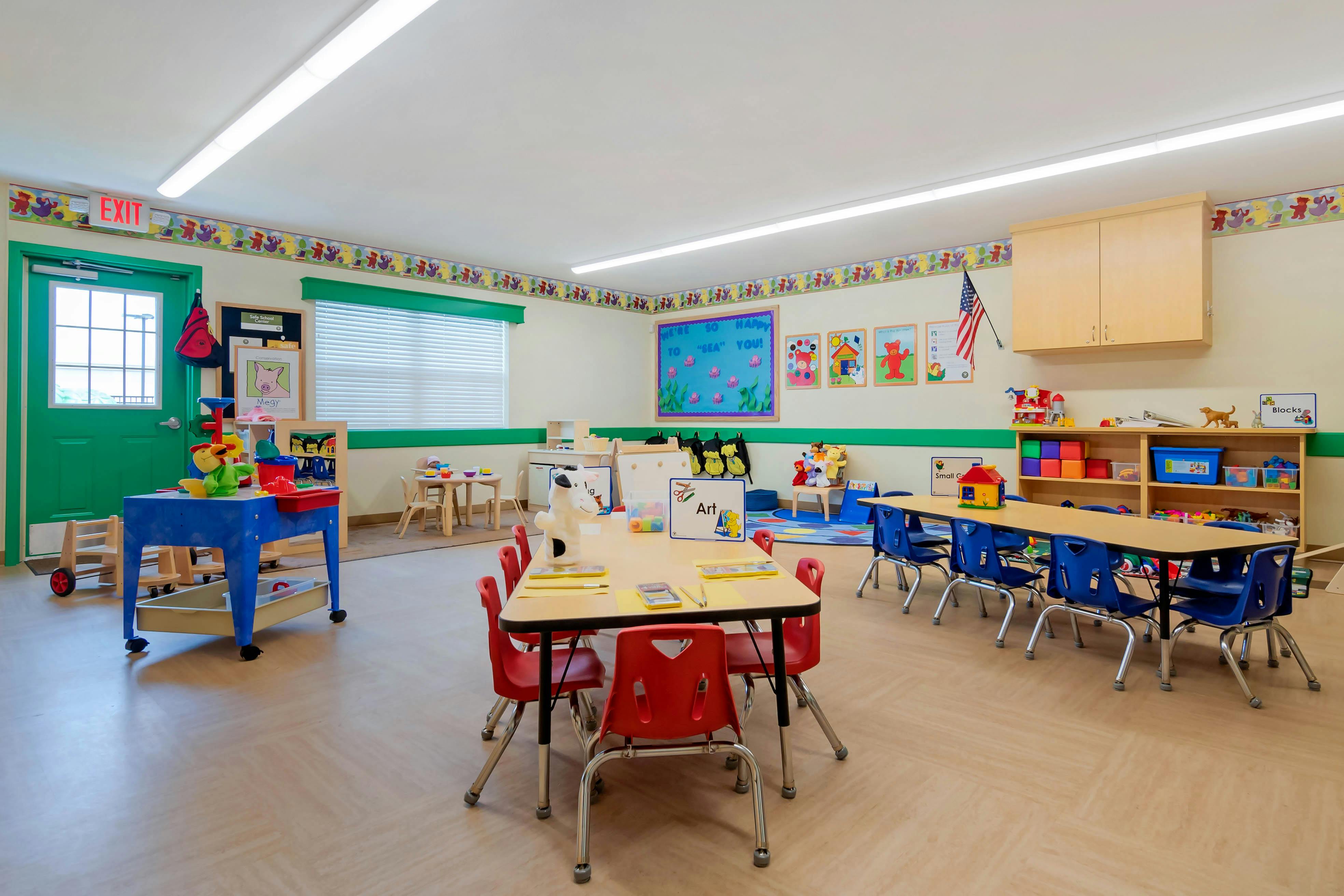 Classroom with child-sized tables and chairs, toys, and educational posters