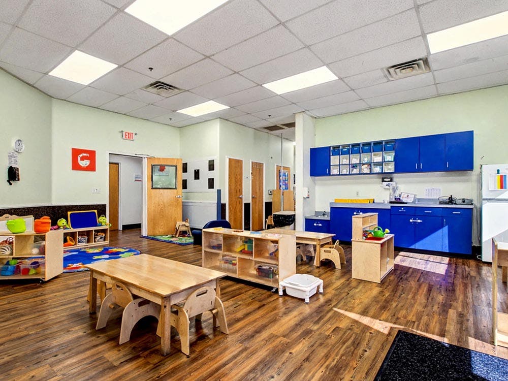 Empty preschool classroom with small tables and chairs