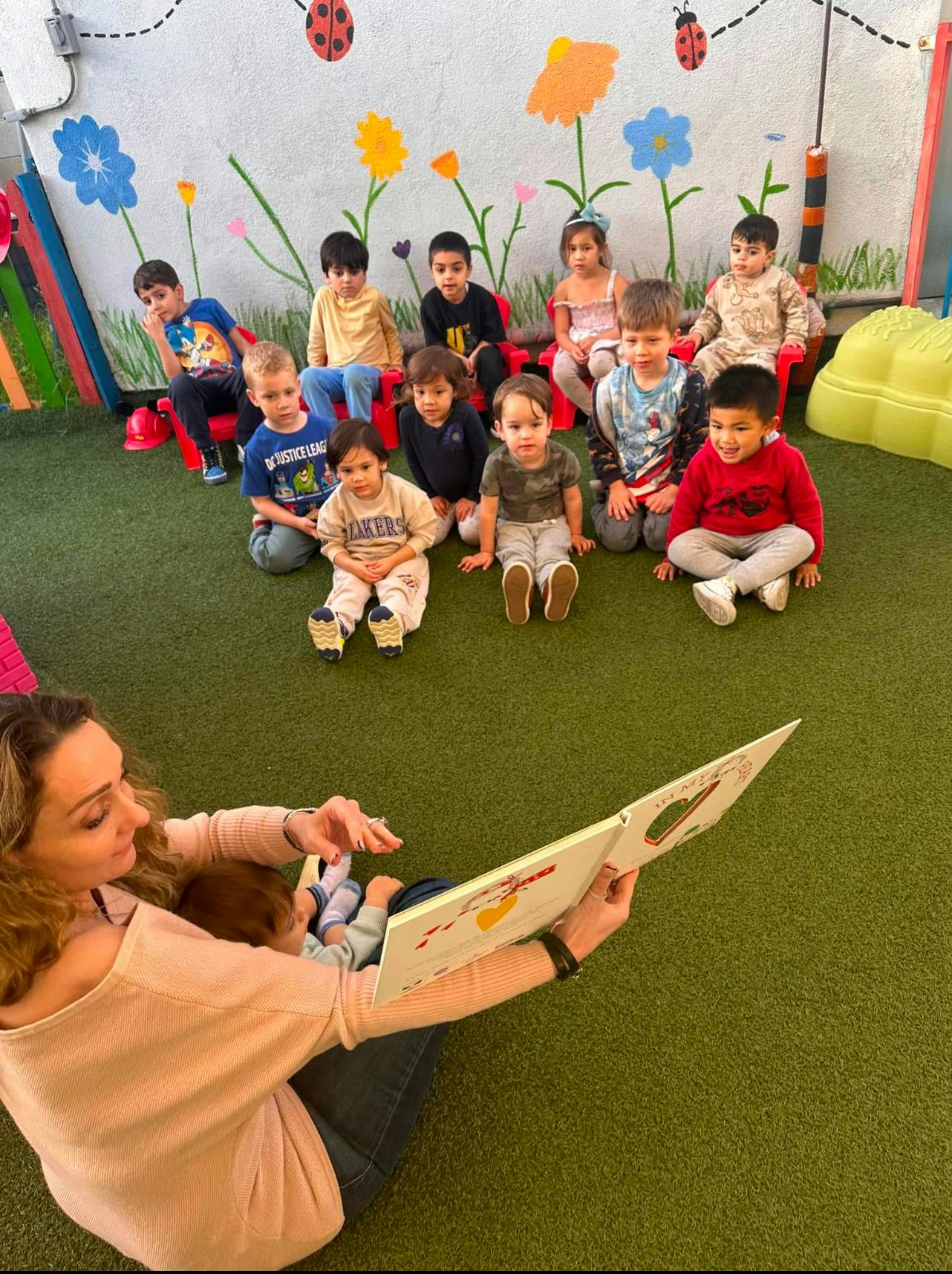 Adult reading a book to children in a classroom
