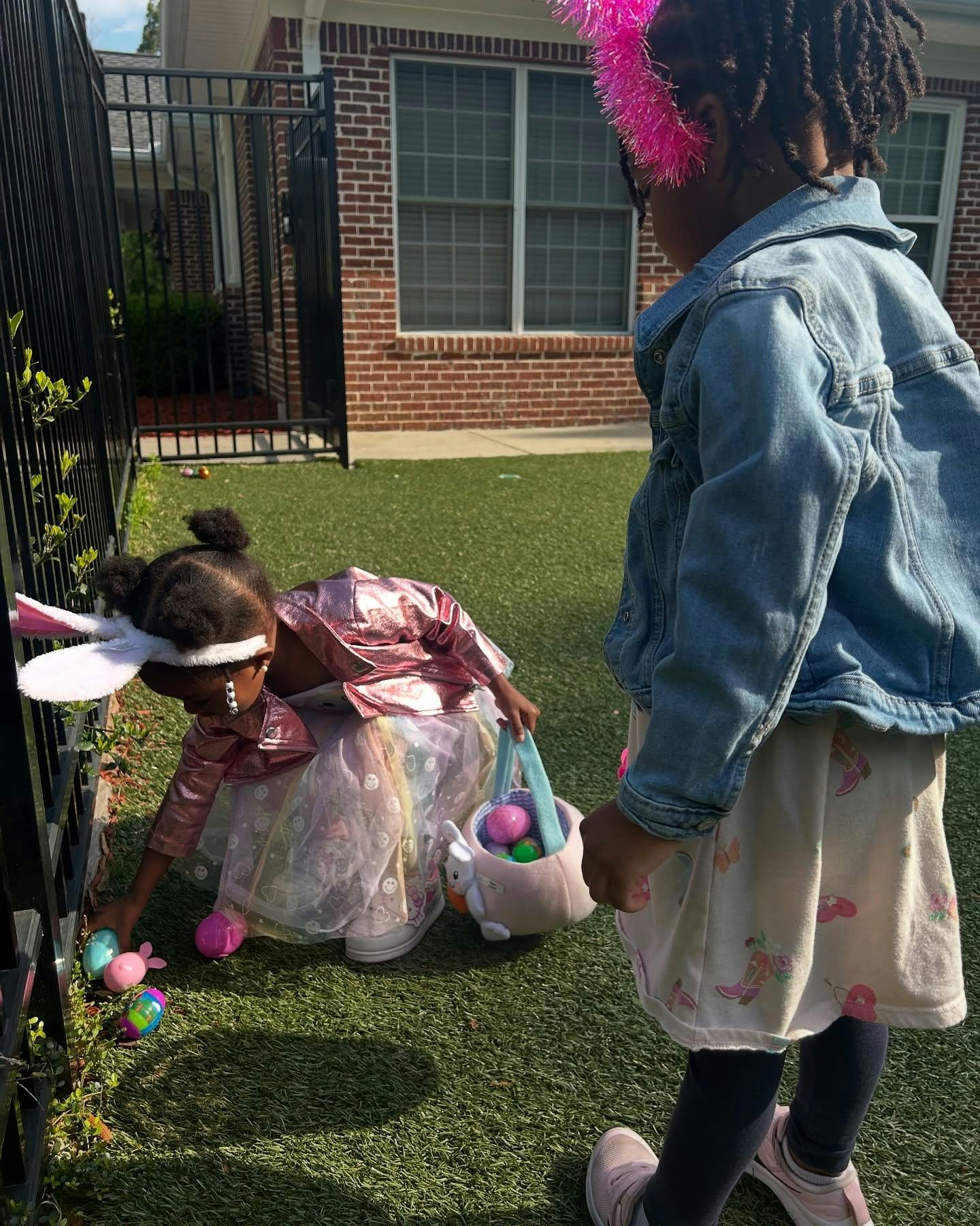 Child in bunny ears collecting eggs in a basket