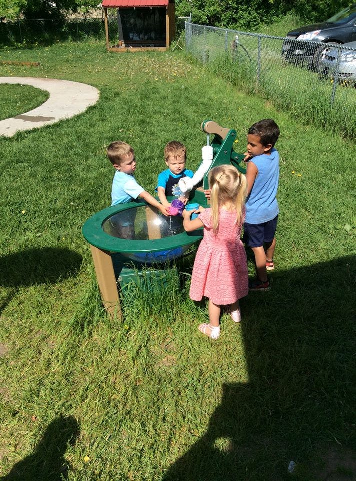 Four children playing with a water table outdoors