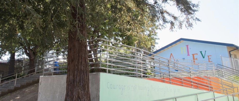 Building with colorful letters on the wall and a ramp with a tree in the foreground